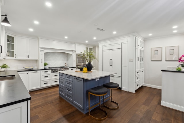 kitchen with white cabinets, a center island, a kitchen breakfast bar, hanging light fixtures, and dark wood-type flooring