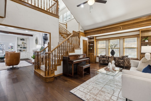 living room with a high ceiling, dark wood-type flooring, built in shelves, and ceiling fan