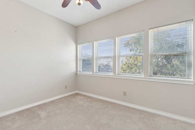 empty room with ceiling fan, light carpet, and plenty of natural light