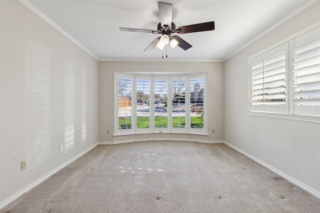 spare room featuring a healthy amount of sunlight, ceiling fan, crown molding, and light colored carpet