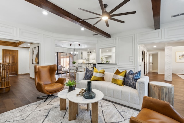 living room with ceiling fan with notable chandelier, light wood-type flooring, crown molding, and beamed ceiling