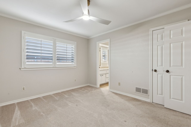 unfurnished bedroom featuring a closet, light carpet, ceiling fan, ornamental molding, and ensuite bathroom