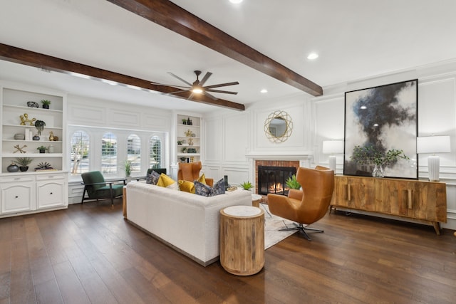 living room with beam ceiling, a brick fireplace, built in features, and dark hardwood / wood-style floors