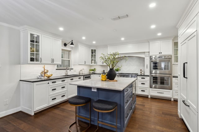 kitchen with stainless steel double oven, dark hardwood / wood-style floors, a kitchen island, white cabinets, and sink