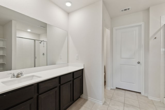 bathroom featuring tile patterned flooring, a shower with shower door, and vanity