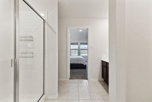 bathroom with a shower with door, vanity, and tile patterned floors