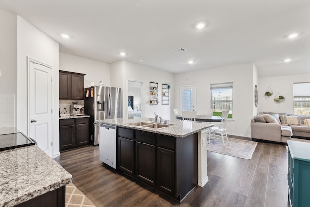 kitchen with sink, stainless steel appliances, a kitchen island with sink, and dark wood-type flooring