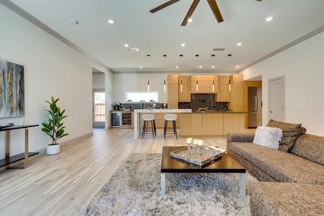 living room with ornamental molding, light wood-type flooring, ceiling fan, and wine cooler