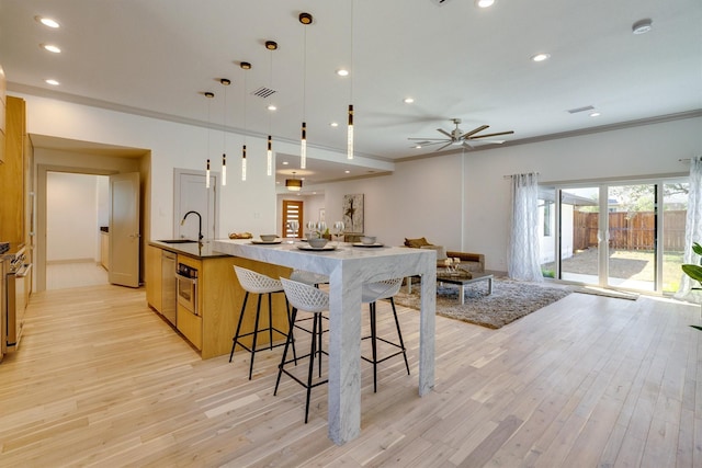 kitchen featuring decorative light fixtures, a large island, light wood-type flooring, and ornamental molding