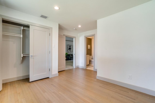 unfurnished bedroom with ensuite bath, a closet, and light wood-type flooring