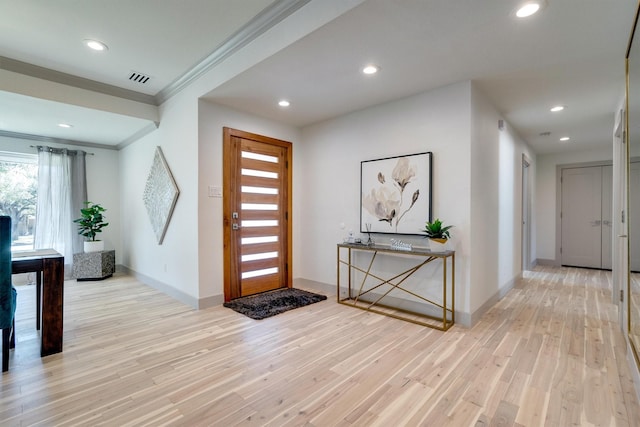 entryway featuring ornamental molding and light hardwood / wood-style flooring