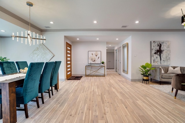 dining room with an inviting chandelier, light wood-type flooring, and crown molding