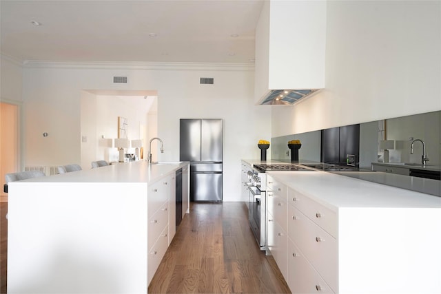 kitchen with stainless steel appliances, a spacious island, hardwood / wood-style flooring, and white cabinetry