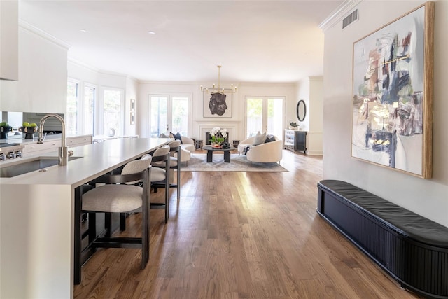 kitchen featuring sink, a kitchen breakfast bar, dark hardwood / wood-style floors, pendant lighting, and crown molding