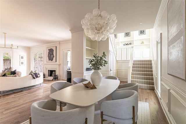 dining area featuring an inviting chandelier, built in features, and hardwood / wood-style flooring