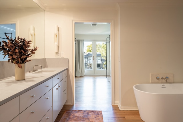 bathroom with a washtub, hardwood / wood-style floors, crown molding, and vanity