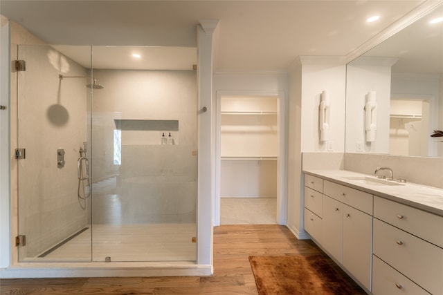 bathroom with ornamental molding, hardwood / wood-style floors, an enclosed shower, and vanity