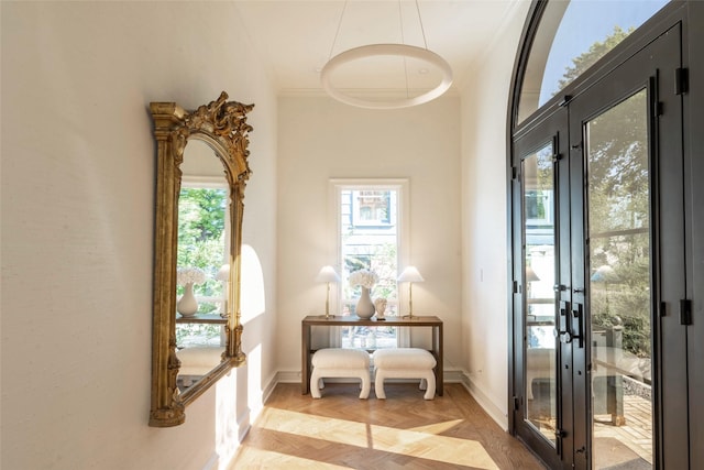 doorway to outside with french doors, light parquet flooring, and ornamental molding