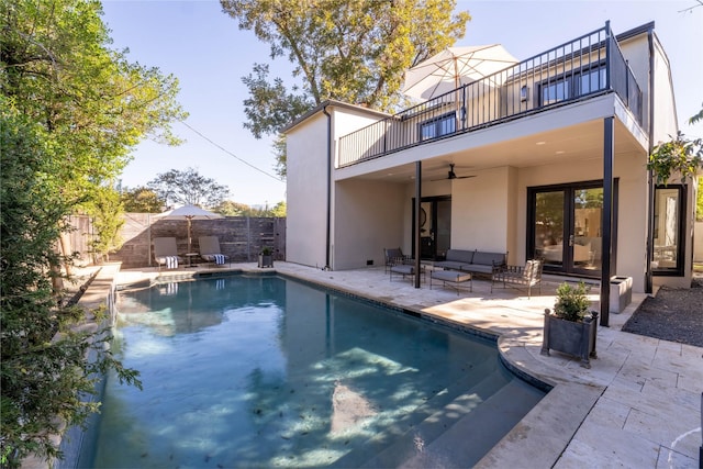 back of property featuring an outdoor hangout area, a balcony, ceiling fan, a patio, and a fenced in pool