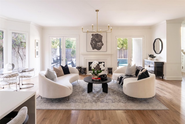 living room featuring ornamental molding, french doors, light hardwood / wood-style flooring, and a chandelier