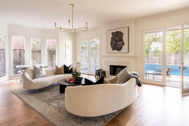 living room featuring french doors, a chandelier, hardwood / wood-style floors, and ornamental molding