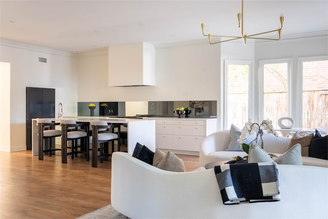 living room featuring light hardwood / wood-style flooring, an inviting chandelier, and crown molding