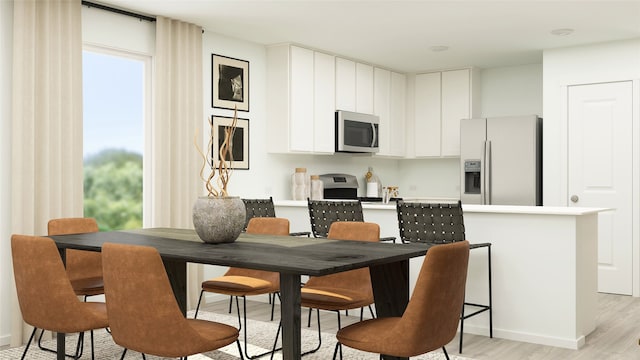 kitchen with stainless steel appliances, white cabinetry, and light hardwood / wood-style floors