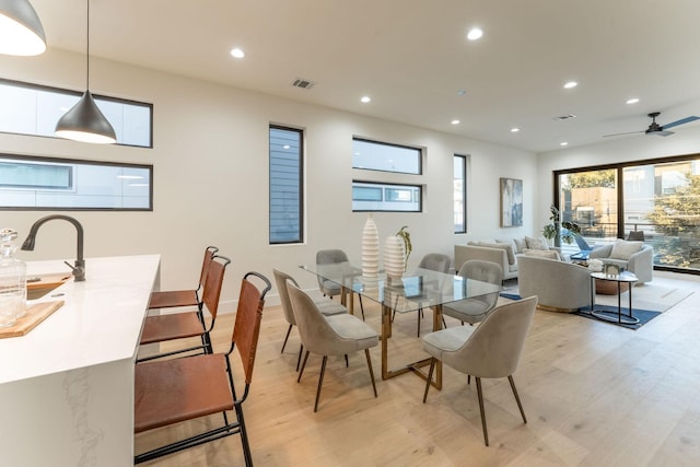 dining area with light hardwood / wood-style floors, ceiling fan, and sink