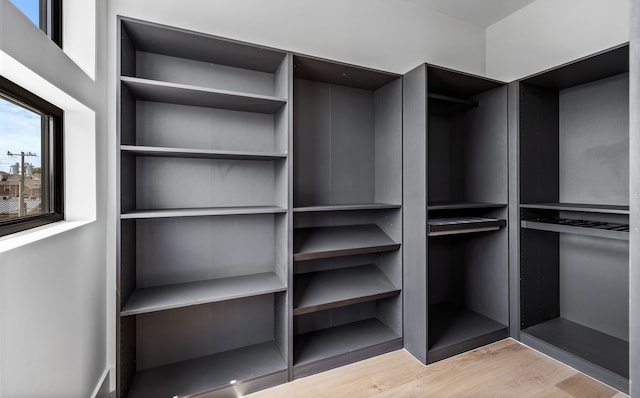 walk in closet with light hardwood / wood-style flooring