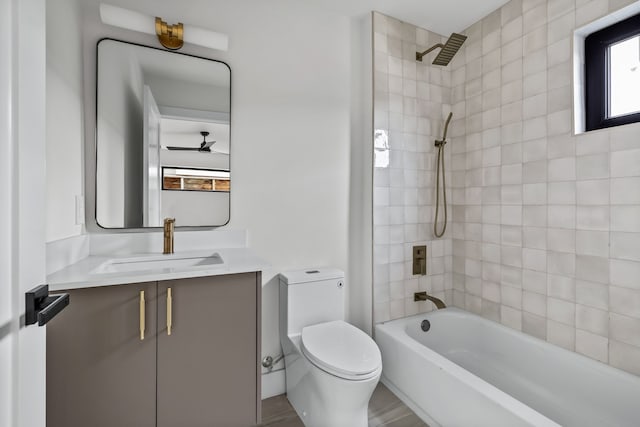 full bathroom featuring toilet, ceiling fan, tiled shower / bath, and vanity