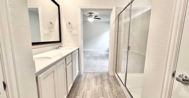 bathroom featuring a shower with door, ceiling fan, and vanity