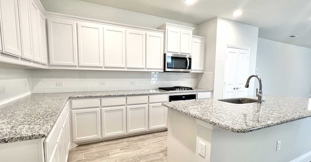 kitchen featuring white cabinets, an island with sink, and sink