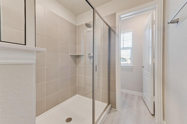 bathroom with a shower with door and wood-type flooring