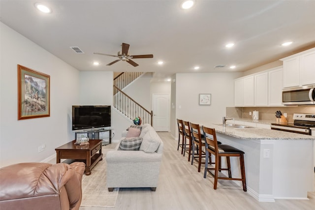 living room featuring sink, ceiling fan, and light wood-type flooring