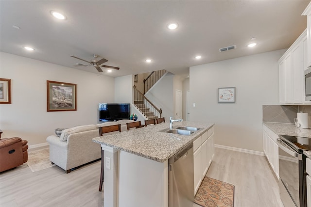 kitchen featuring stainless steel appliances, white cabinetry, sink, and a center island with sink