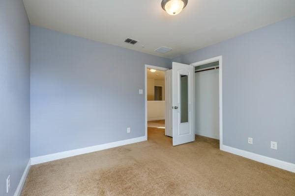 unfurnished bedroom with light colored carpet and a closet