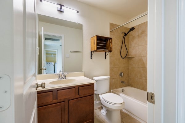 full bathroom with toilet, tiled shower / bath, tile patterned floors, and vanity