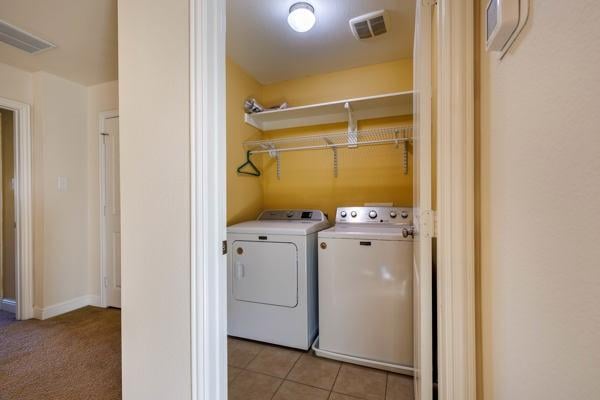 washroom with light tile patterned floors and washer and clothes dryer