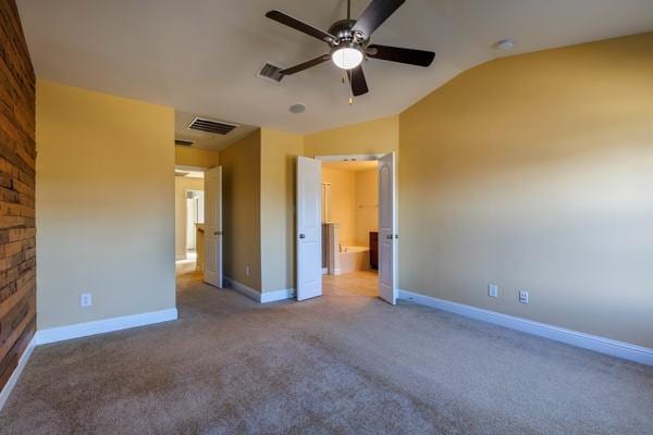 unfurnished bedroom featuring ceiling fan, light colored carpet, ensuite bathroom, and vaulted ceiling