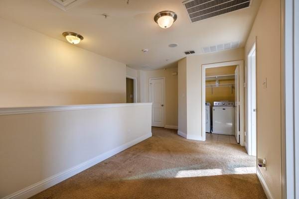 corridor with light carpet and separate washer and dryer