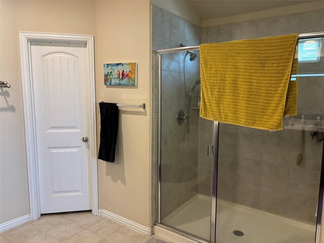 bathroom with a shower with door and tile patterned flooring