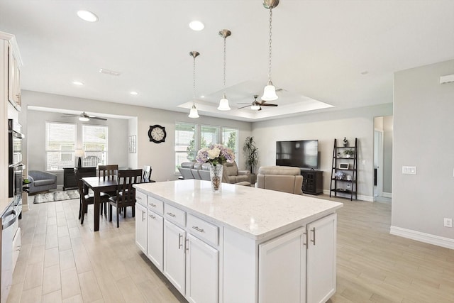 kitchen with decorative light fixtures, white cabinetry, a tray ceiling, and a center island