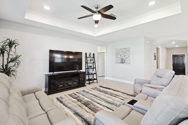 living room featuring ornamental molding, a raised ceiling, and ceiling fan