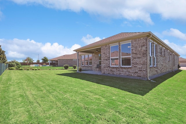 rear view of property featuring a yard, ceiling fan, and a patio