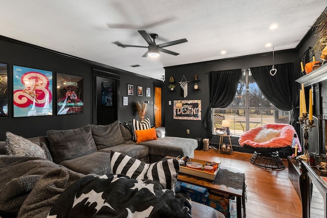 living room featuring a textured ceiling, ceiling fan, ornamental molding, and hardwood / wood-style flooring