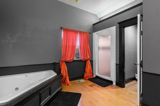 bathroom featuring hardwood / wood-style floors, vaulted ceiling, and a bathing tub