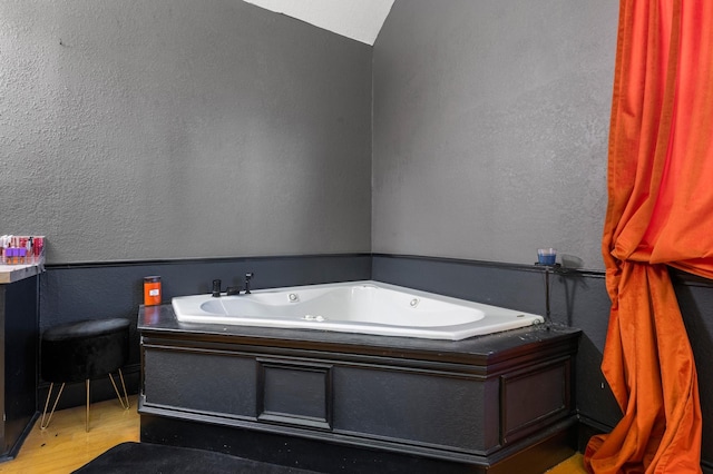 bathroom with lofted ceiling, hardwood / wood-style flooring, and a bath