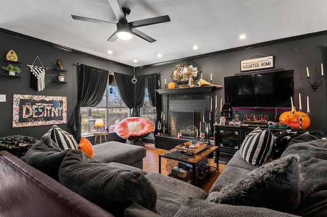 living room with a brick fireplace, hardwood / wood-style floors, ceiling fan, and crown molding