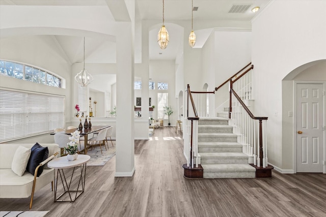 entrance foyer with a towering ceiling, a notable chandelier, and hardwood / wood-style floors