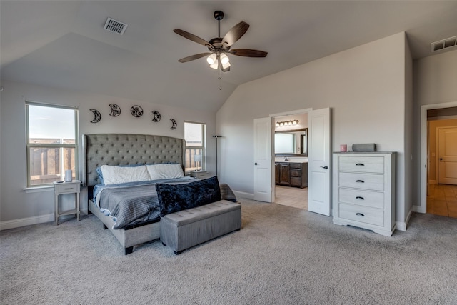 carpeted bedroom with ceiling fan, lofted ceiling, and ensuite bath